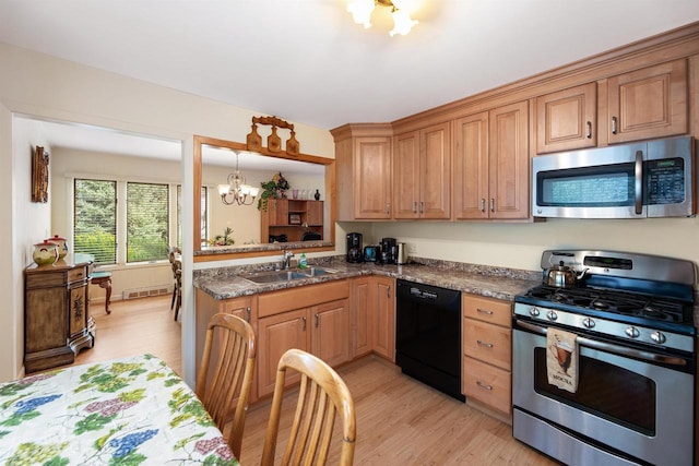 kitchen featuring kitchen peninsula, sink, an inviting chandelier, light hardwood / wood-style flooring, and appliances with stainless steel finishes