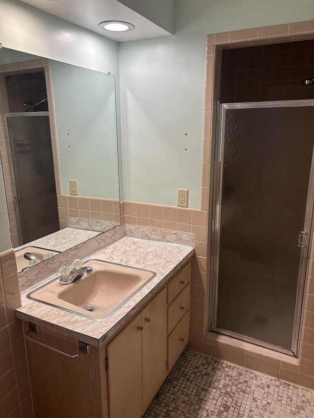 bathroom featuring tile walls, a shower with door, vanity, and tile patterned flooring