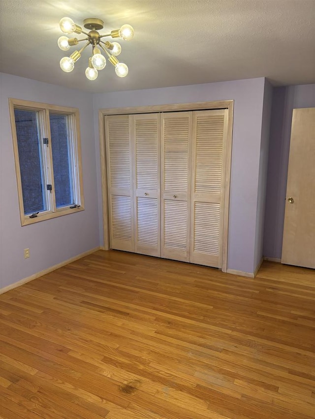 unfurnished bedroom with a closet, light wood-type flooring, a chandelier, and a textured ceiling