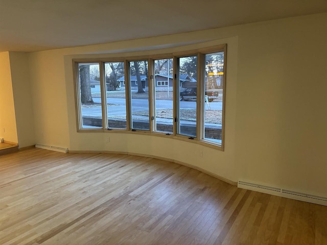 unfurnished room featuring a baseboard radiator and light wood-type flooring