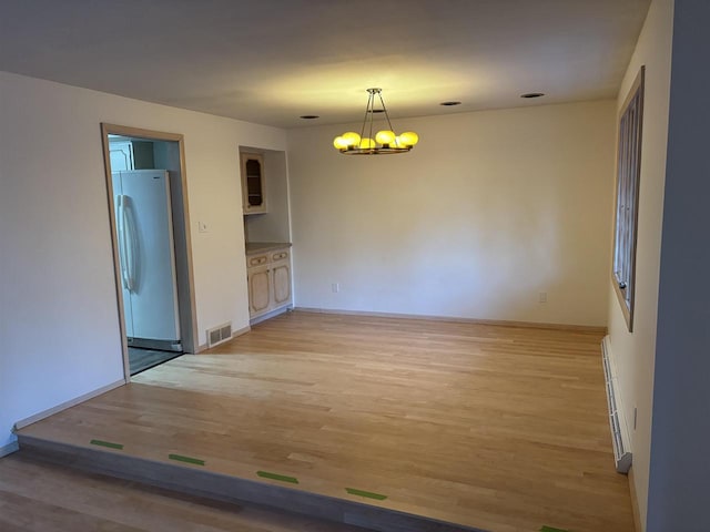 interior space featuring baseboard heating, light hardwood / wood-style flooring, and a chandelier