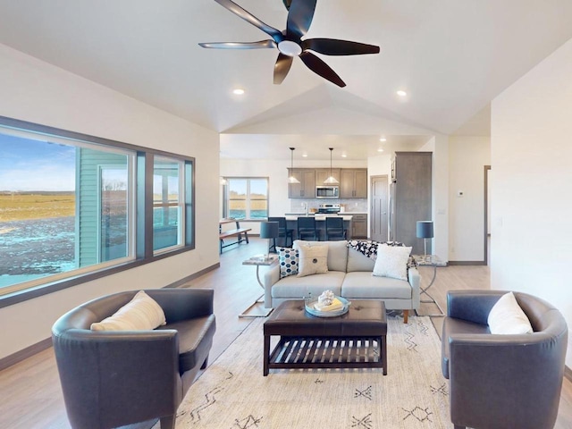 living room featuring ceiling fan, light hardwood / wood-style floors, and lofted ceiling