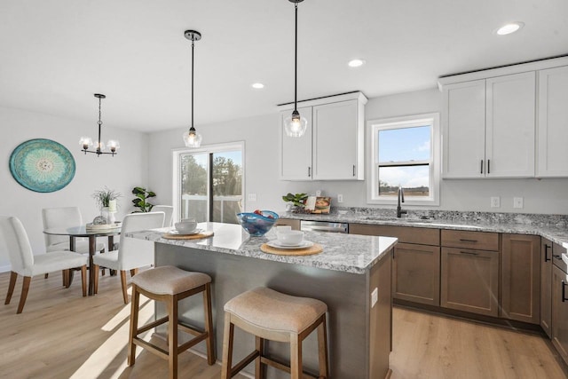 kitchen featuring decorative light fixtures, light hardwood / wood-style floors, white cabinets, and sink