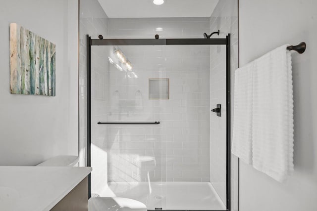 bathroom with toilet, a shower with door, and vanity