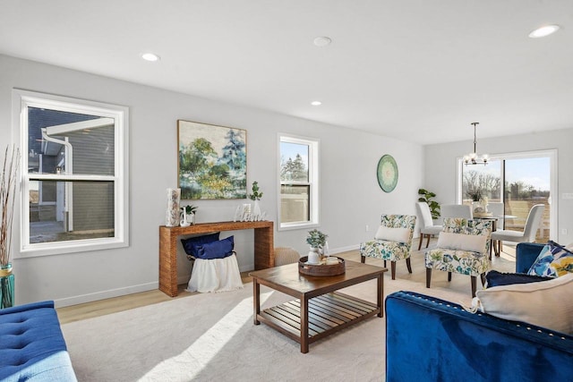 living room with light wood-type flooring, a healthy amount of sunlight, and a notable chandelier