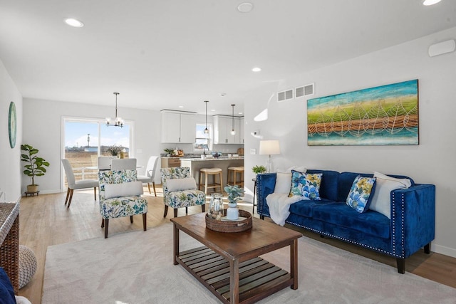 living room featuring light wood-type flooring and a notable chandelier