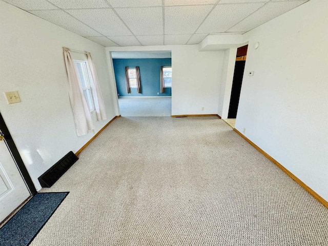 carpeted empty room with a paneled ceiling