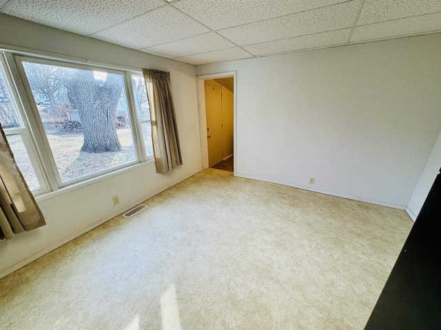 carpeted spare room featuring a drop ceiling