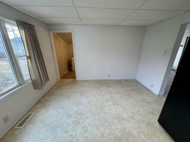 spare room featuring light colored carpet and a paneled ceiling