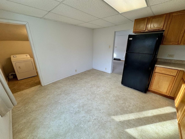 kitchen with light carpet, black refrigerator, a drop ceiling, and washer / clothes dryer