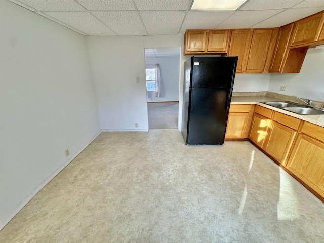 kitchen with sink, black fridge, and a paneled ceiling