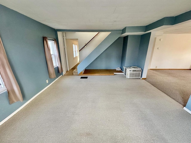 unfurnished living room featuring a wall mounted AC and carpet flooring