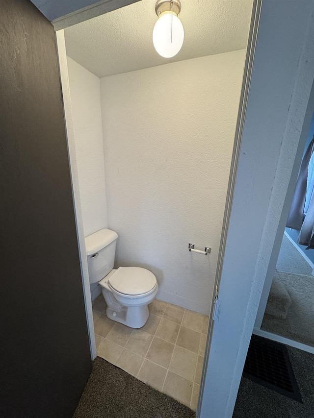 bathroom with toilet and a textured ceiling