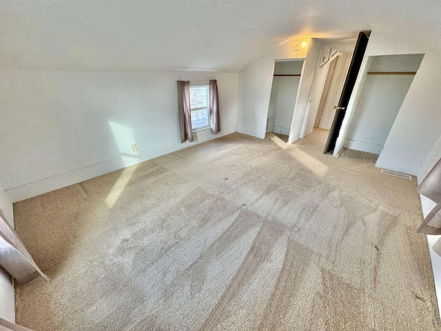 unfurnished bedroom featuring light colored carpet and lofted ceiling