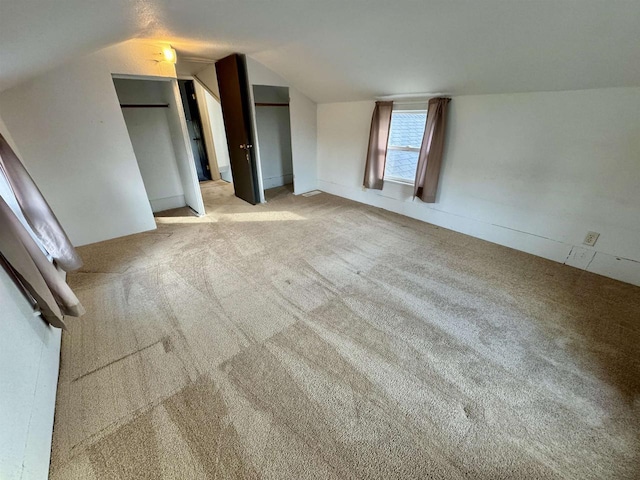 unfurnished bedroom featuring lofted ceiling and light carpet