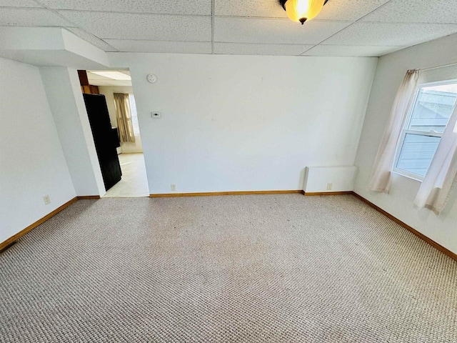 carpeted spare room featuring plenty of natural light and a drop ceiling