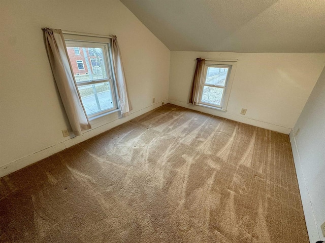 additional living space with lofted ceiling, light colored carpet, and plenty of natural light