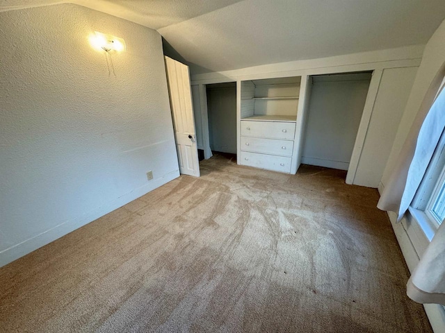 unfurnished bedroom featuring light colored carpet, a textured ceiling, and vaulted ceiling