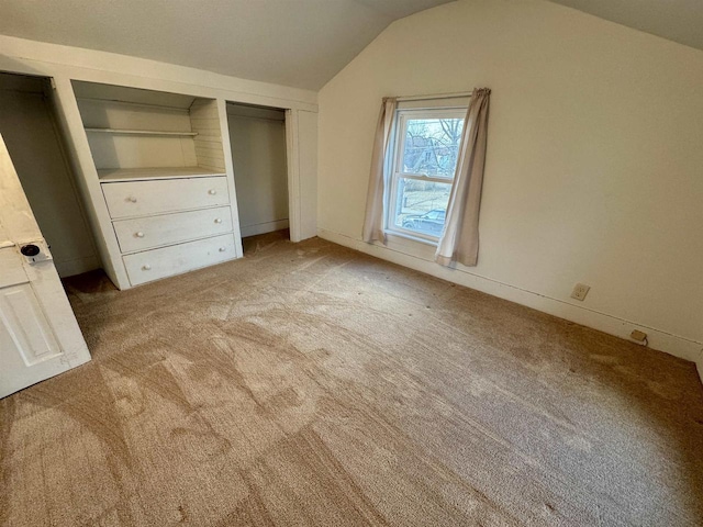 unfurnished bedroom featuring lofted ceiling and light colored carpet