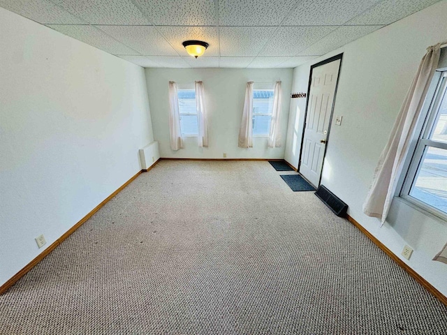 carpeted empty room with a drop ceiling and radiator heating unit