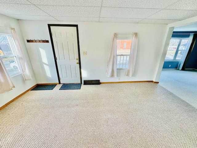 interior space featuring a paneled ceiling, carpet, and a wealth of natural light