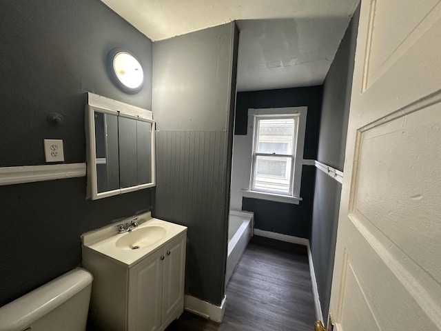 bathroom with vanity, a bathtub, hardwood / wood-style flooring, and toilet