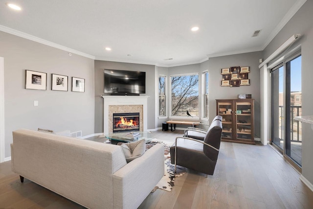 living room featuring hardwood / wood-style flooring, a healthy amount of sunlight, ornamental molding, and a fireplace