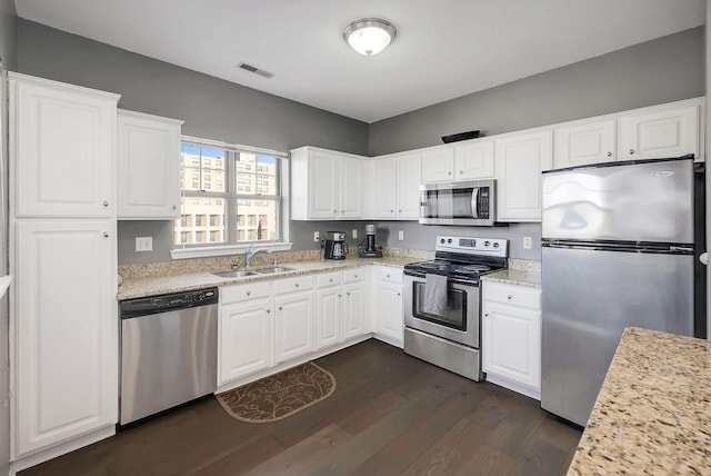 kitchen with appliances with stainless steel finishes, sink, dark hardwood / wood-style flooring, and white cabinetry