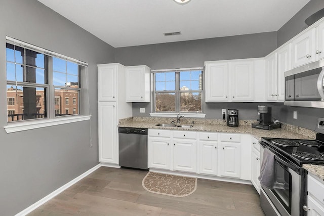 kitchen with hardwood / wood-style floors, stainless steel appliances, white cabinets, and sink