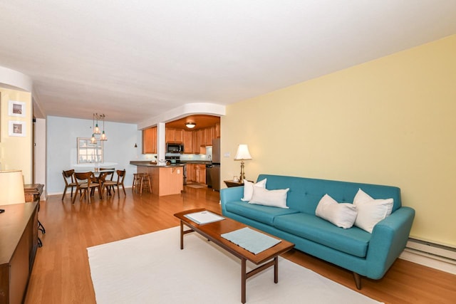 living room with baseboard heating and light hardwood / wood-style flooring