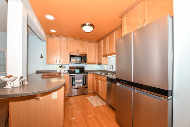 kitchen featuring kitchen peninsula, appliances with stainless steel finishes, light brown cabinetry, light hardwood / wood-style flooring, and sink