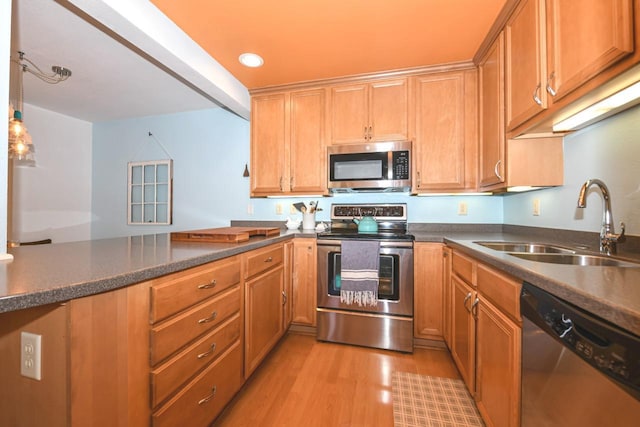 kitchen featuring kitchen peninsula, stainless steel appliances, decorative light fixtures, light wood-type flooring, and sink