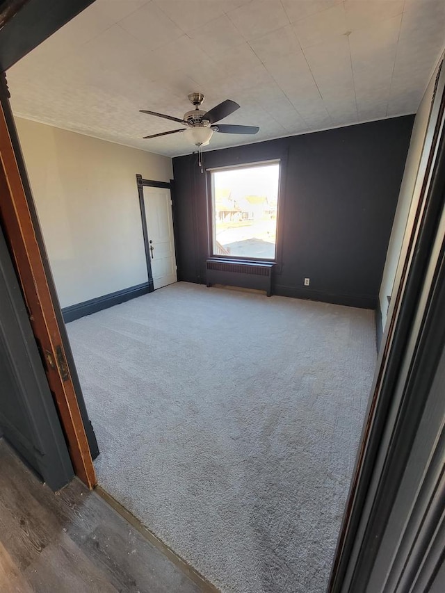 unfurnished room featuring ceiling fan, light colored carpet, and radiator