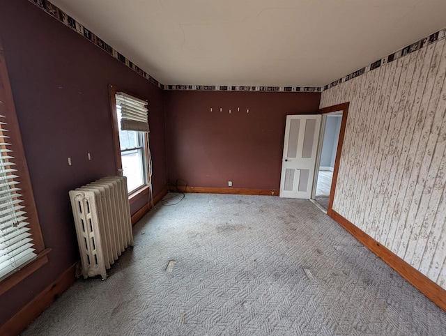 empty room featuring radiator and light carpet