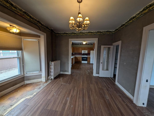 unfurnished dining area with a notable chandelier, radiator, and dark wood-type flooring