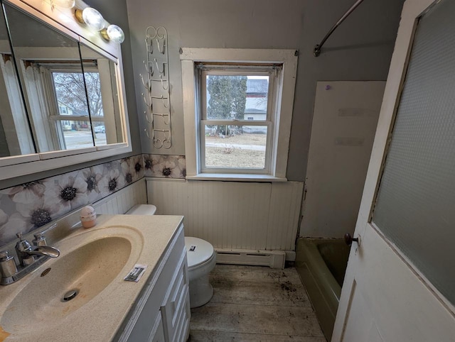 full bathroom with a baseboard heating unit, vanity, toilet, and a healthy amount of sunlight