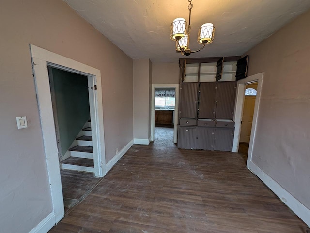 unfurnished dining area featuring a notable chandelier and dark wood-type flooring