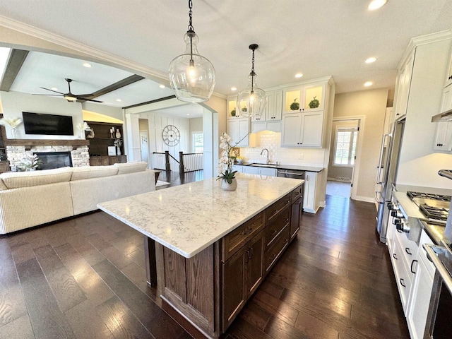 kitchen featuring decorative light fixtures, a center island, beam ceiling, sink, and white cabinets