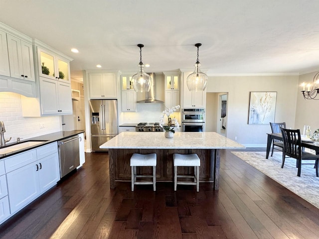 kitchen featuring decorative light fixtures, white cabinets, stainless steel appliances, and a center island