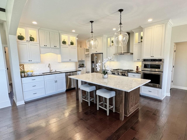 kitchen with pendant lighting, a kitchen island, sink, white cabinetry, and stainless steel appliances