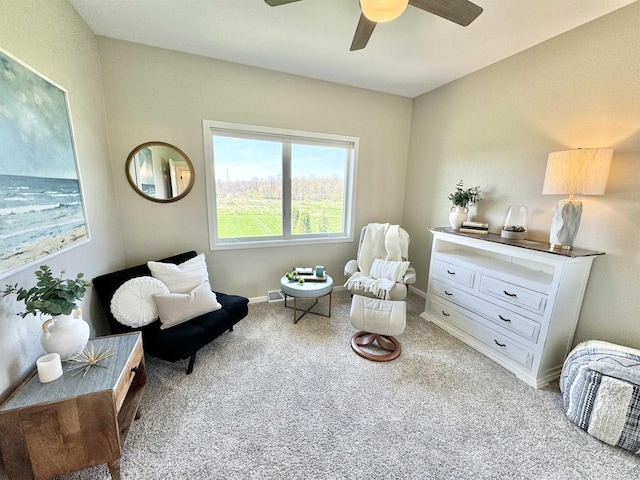 living area with light carpet and ceiling fan