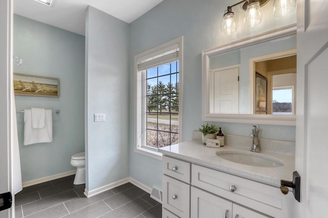 bathroom with toilet, vanity, and tile patterned flooring