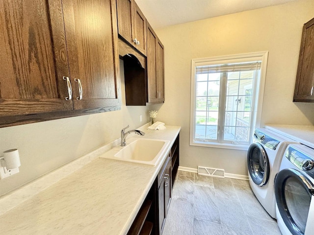 laundry room with sink, washing machine and clothes dryer, and cabinets