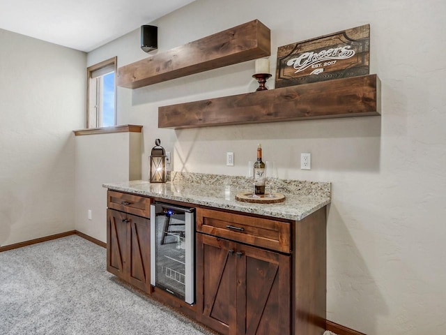 bar featuring light stone counters, light colored carpet, and beverage cooler