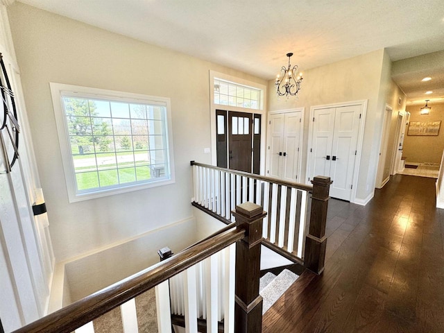 entryway with dark wood-type flooring and a notable chandelier