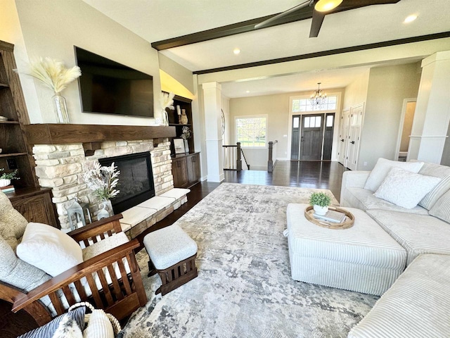 living room with hardwood / wood-style flooring, an inviting chandelier, beamed ceiling, and a fireplace