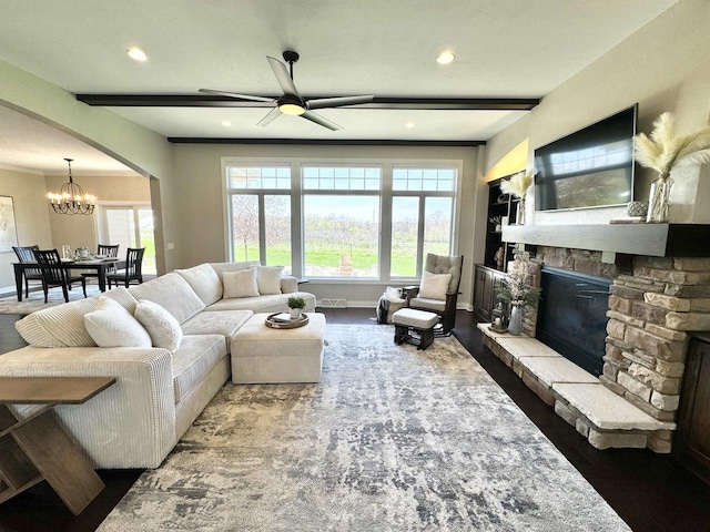 living room with wood-type flooring, a fireplace, beamed ceiling, and ceiling fan with notable chandelier