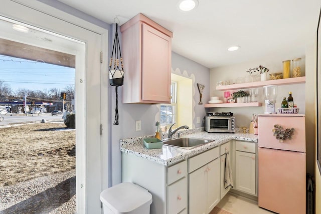 kitchen with light stone countertops, sink, a wealth of natural light, and refrigerator