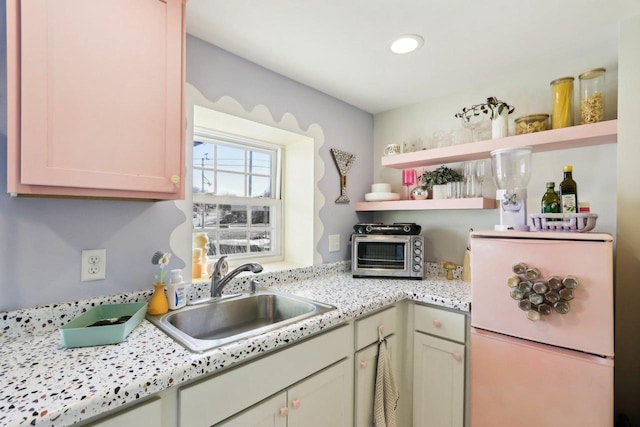 kitchen with sink, light stone countertops, and white fridge