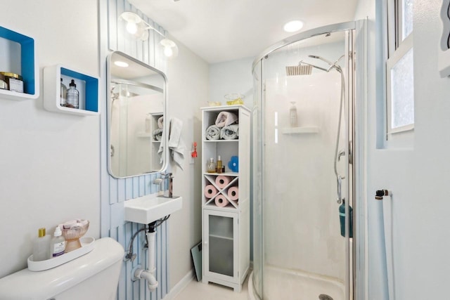 bathroom with sink, a shower with door, and toilet